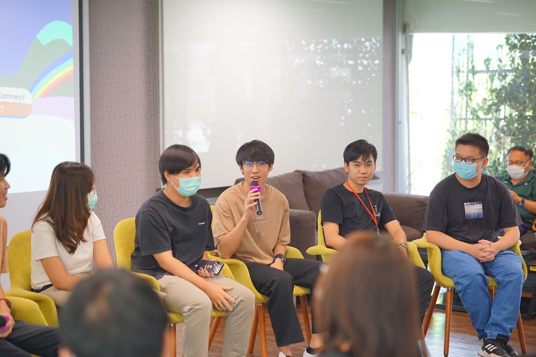 Thanyapisit speaking with a microphone during a community panel